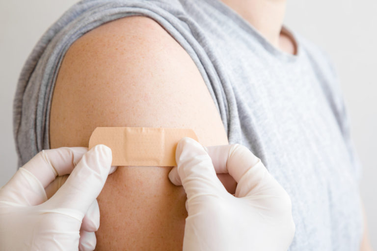 patient's arm getting band-aid put on after flu shot