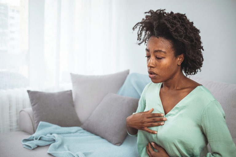 woman in discomfort holding onto chest and stomach and experiencing heartburn