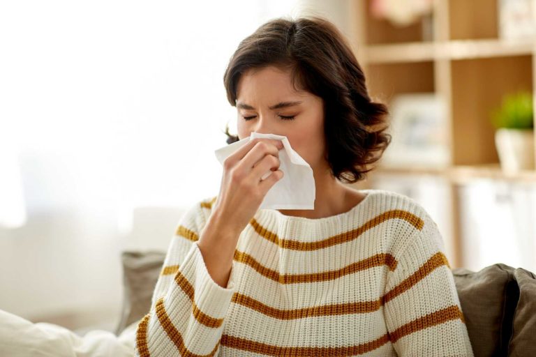 lady with seasonal allergies wiping her runny nose with a tissue